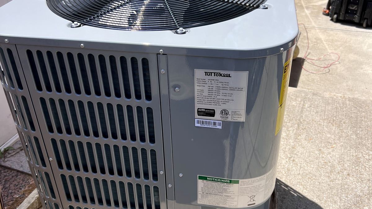 New central air conditioning condenser being prepared for installation